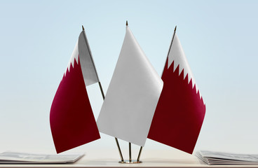 Two flags of Qatar with a white flag in the middle