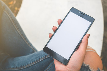Hand holding black mobile smart phone with blank white screen at outdoor to checking e-mail or social network. technology and lifestyle concept.