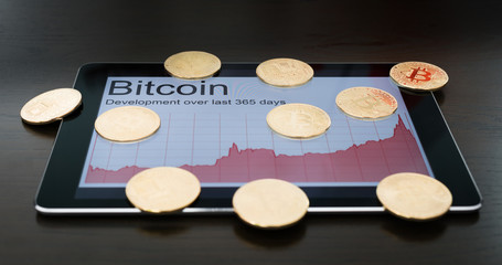 Bitcoins and rising chart on digital tablet