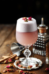 pink cocktail with foam, decorated with pink buds, on the bar.