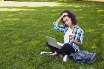 Pensive young woman using laptop in park