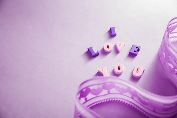 I love you lettering with a ribbon on purple background. Valentine's day concept.