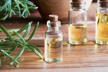 A bottle of rosemary essential oil with fresh rosemary twigs