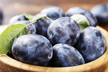 Obraz premium ripe plums on a wooden background, top view