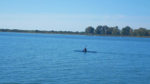 A man kayaking floats along the water