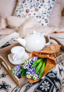 Bouquet hyacinth flowers and teapot with fresh tea are on bed