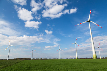 große Windräder stehen auf einem Feld und produzieren Ökostrom