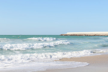 Breathtaking waves running up on the sandy beach. Sunny day and sea storm. Beauty of the raging...