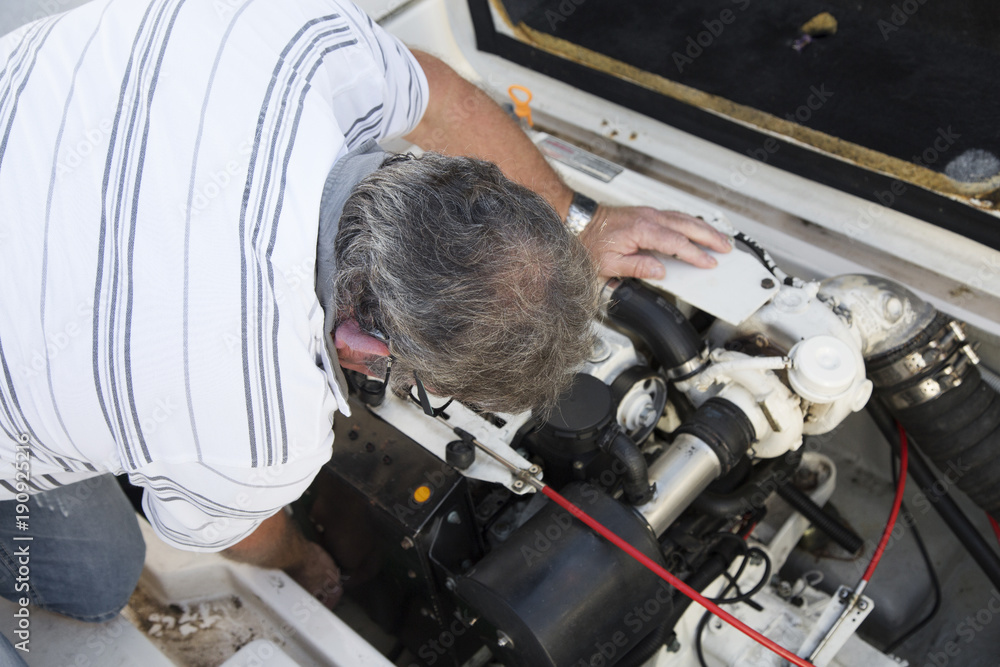 Wall mural close-up of a man repairing a boat engine