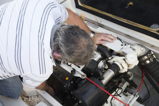 close-up of a man repairing a boat engine