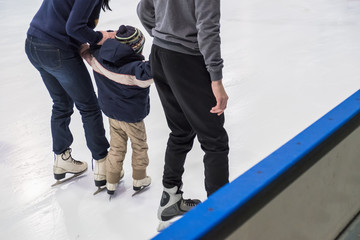 Happy family indoor ice skating at rink. Winter