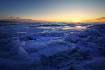 Beautiful winter landscape with sunset fiery sky and frozen lake. Composition of nature.
