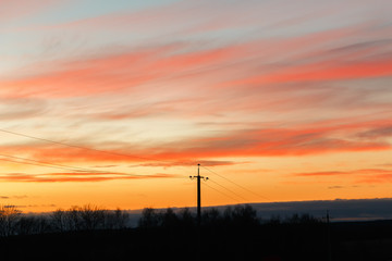 Naklejka premium Silhouette of high voltage power lines against the background of dramatic sky at sunset.