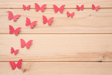 Fototapeta premium Superficie de madera con mariposas rosas de papel en el lateral izquierdo.