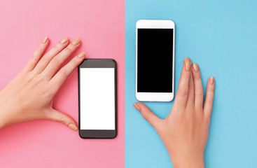 female hands hold two phones black and white.