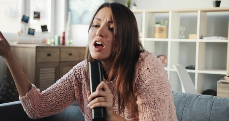 Pretty Ukrainian girl dancing and singing television karaoke on weekend. Young woman singing favorite songs in living room in apartment. - Powered by Adobe