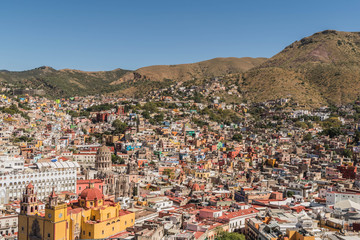Looking down from above, on a UNESCO Heritage Site-Guanajuato City, Mexico, from up on a hill, with a view of the Basilica, Guanajuato University, many other buildings and colorful houses - 190929029