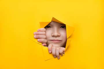 girl looking through a hole in colored paper