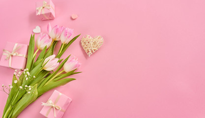Fototapeta na wymiar Valentines Day background with pink tulips, gift box and hearts over pink background. Space for text