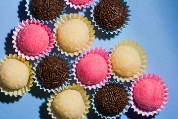 Brigadeiro Beijinho and Bicho de Pe: sweets from Brazil. Child birthday party. Overhead of candy ball on blue table.