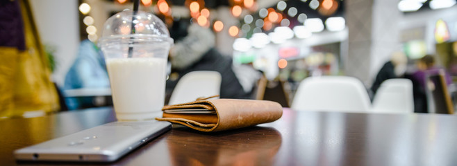 wallet mobile and cup with milk shake on table - obrazy, fototapety, plakaty
