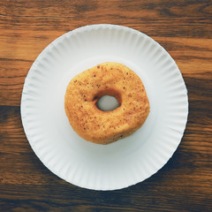 Top view of donut on cardboard plate on wooden table
