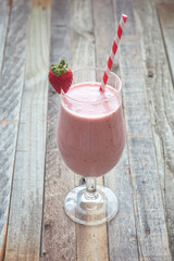 Delicious strawberry smoothie on wooden background