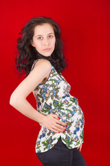 Beautiful pregnant girl on red background