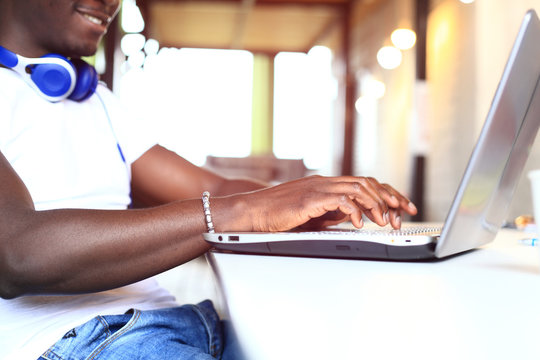 Full concentration. Close-up part of young African man using laptop while sitting at his working place