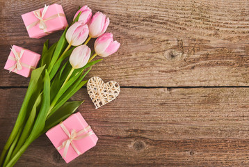 Valentines day background with pink tulips and gift box over wood board