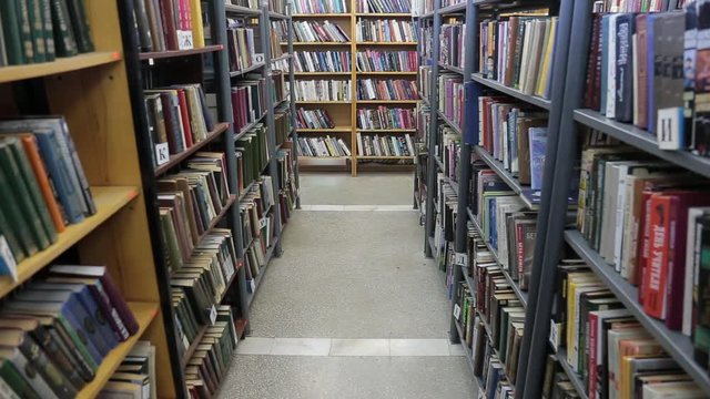 Books on shelves. Sliding camera in library. Bookstore