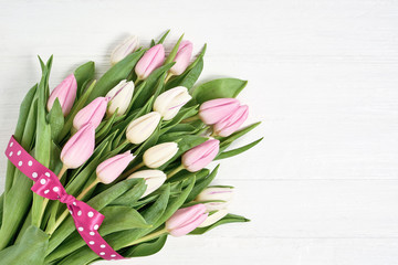 Pink and white tulips bouquet decorated with ribbon. Copy space, top view