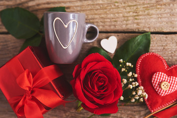 Valentines day background with red rose, hearts and gift box over wood board