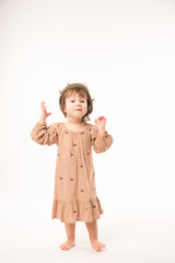 Cute little girl in beige dress with gold crown isolated on white background. Portrait of happy little girl.