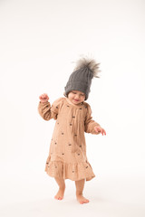 Portrait of happy little girl. Cute little girl in beige dress in a gray hat isolated on white background.