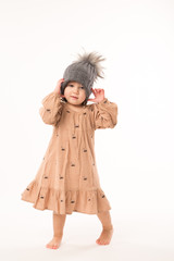 Portrait of happy little girl. Cute little girl in beige dress in a gray hat isolated on white background.