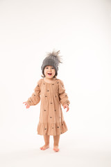 Portrait of happy little girl. Cute little girl in beige dress in a gray hat isolated on white background.