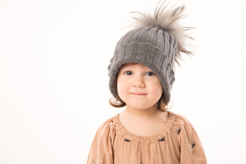 Portrait of happy little girl. Cute little girl in beige dress in a gray hat isolated on white background.