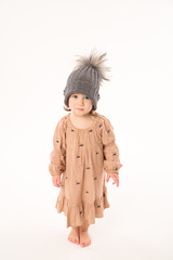 Portrait of happy little girl. Cute little girl in beige dress in a gray hat isolated on white background.