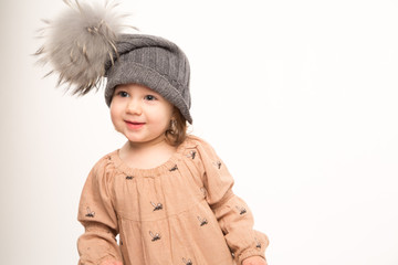 Portrait of happy little girl. Cute little girl in beige dress in a gray hat isolated on white background.