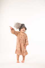 Portrait of happy little girl. Cute little girl in beige dress in a gray hat isolated on white background.