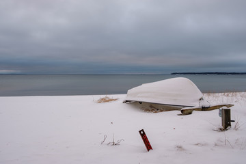Snow covered boat upside down on the beach