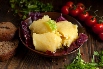 mashed potatoes, bread, greens and cherry tomatoes on a dark wooden table