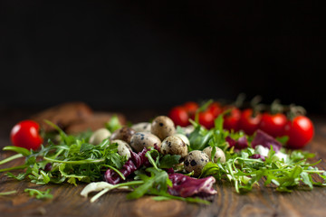 quail eggs and greens on a dark wooden table