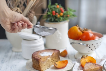 sweet homemade pastries with persimmons, on white tableware and white background, sprinkled with powdered sugar. Free method for text.