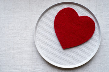 Rustic red felted heart on gray plate with tile background