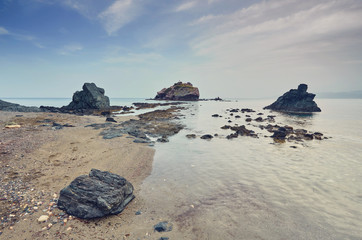 Stones and rocks in forefront with creamy surf ebbing and flowing on Polis beach, Cyprus.