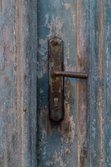 Old vintage metal door handle on old blue wooden doors. Rusty door handle