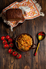 stewed cabbage, bread and cherry tomatoes on a dark wooden table