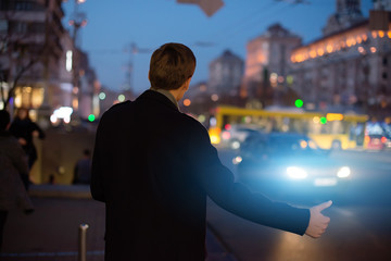 The guy stops a taxi at night. Man stops hitchhiking.